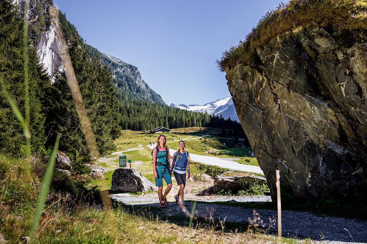 Zwei Wanderinnen im Habachtal in der Wildkogel-Arena, umgeben von Wäldern, Felsformationen und Gletscherblick – unberührte Natur im Nationalpark Hohe Tauern erleben.